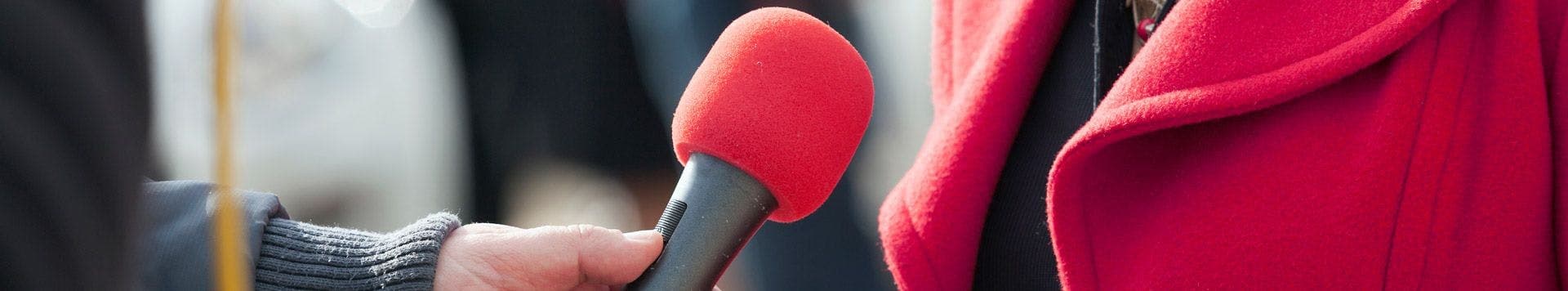 Woman in pink being interviewed, representing media, reputation, and privacy legal services at JMW Solicitors.